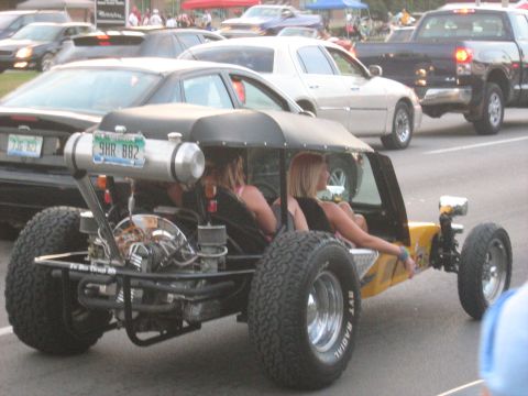 1988 Mercury Grand Marquis - A custom-built yellow dune buggy cruises down the road, its exposed engine and large tires a stark contrast to the surrounding sedans and t…