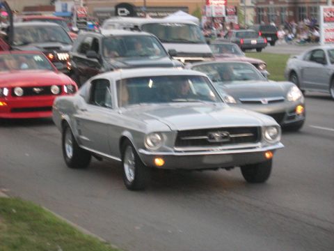 1988 Mercury Grand Marquis - Classic Ford Mustang coupe driving in a parade or car show with other vehicles.