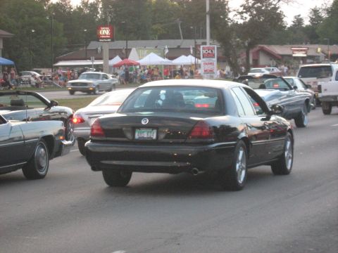 1988 Mercury Grand Marquis - A black sedan drives in traffic during a summer event.