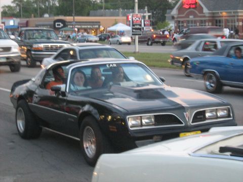 1988 Mercury Grand Marquis - A black Pontiac Firebird Trans Am is seen in traffic with several other vehicles.