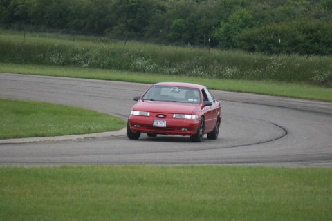 1992 Ford Taurus - A red 1992 Ford Taurus sedan navigates a curve on a race track.
