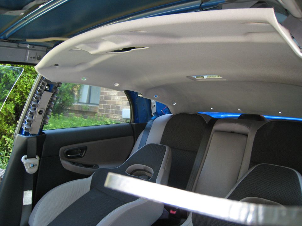 Interior of a 2007 Subaru Impreza showing the headliner removed, rear seats, and door panel