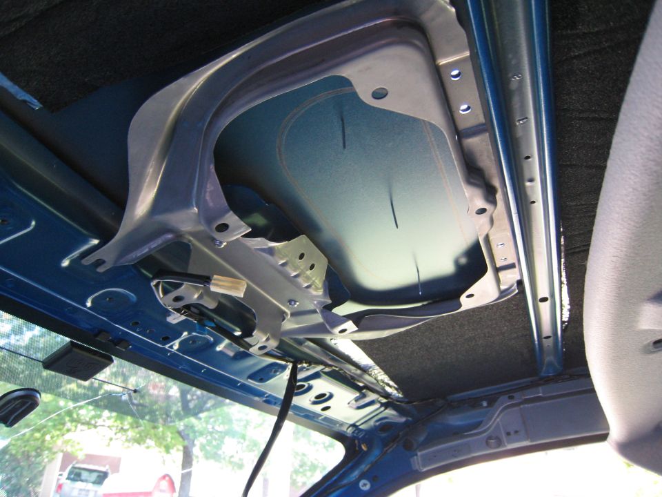 Car roof interior with headliner removed showing bare blue metal and wiring