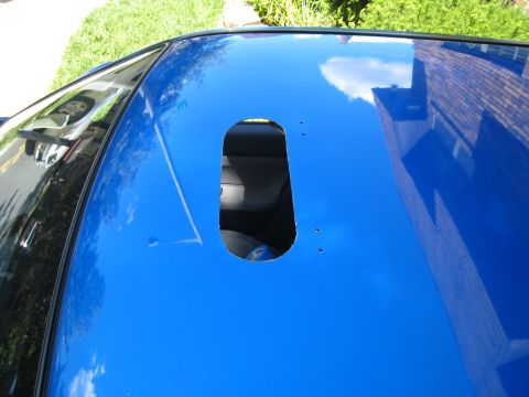 2007 Subaru Impreza - Car roof cutout reveals interior; building reflection visible on the blue paint.