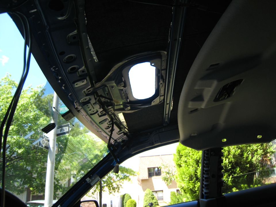 Hole cut in a car roof seen from inside with headliner dropped and wiring across roof bows