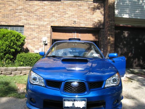 2007 Subaru Impreza - A blue 2007 Subaru Impreza is parked in front of a brick building with its driver's side door open.