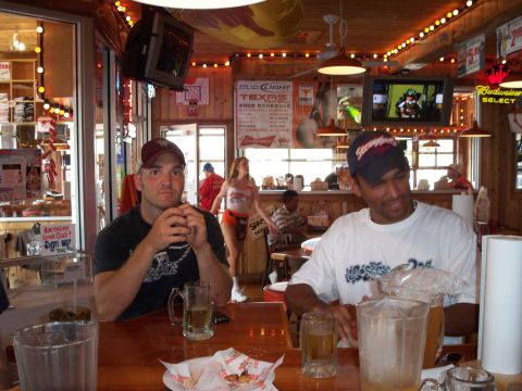 1996 Ford Bronco - Two men sit at a table in a Hooters restaurant, with a waitress walking in the background.
