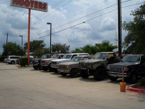 1996 Ford Bronco - Several Ford Broncos and F-Series trucks are parked in a lot near a Hooters restaurant.
