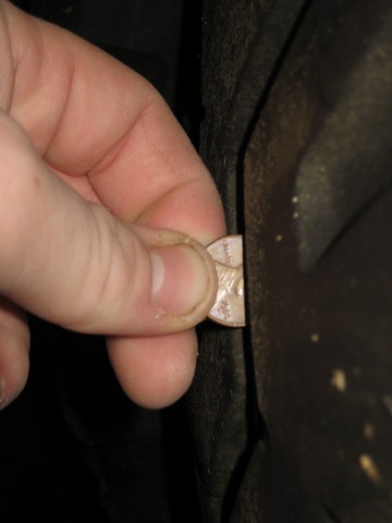 1995 Ford Bronco - A hand uses a penny to check the tire tread depth on a vehicle.