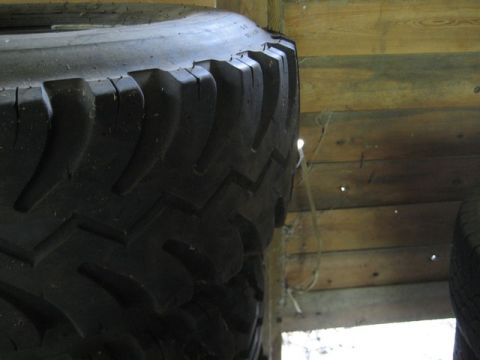 1995 Ford Bronco - A close-up view of a tire's tread pattern, set against a backdrop of weathered wooden planks.