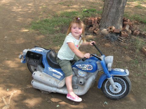 1994 Ford Bronco - Child on a blue toy motorcycle in a yard setting.