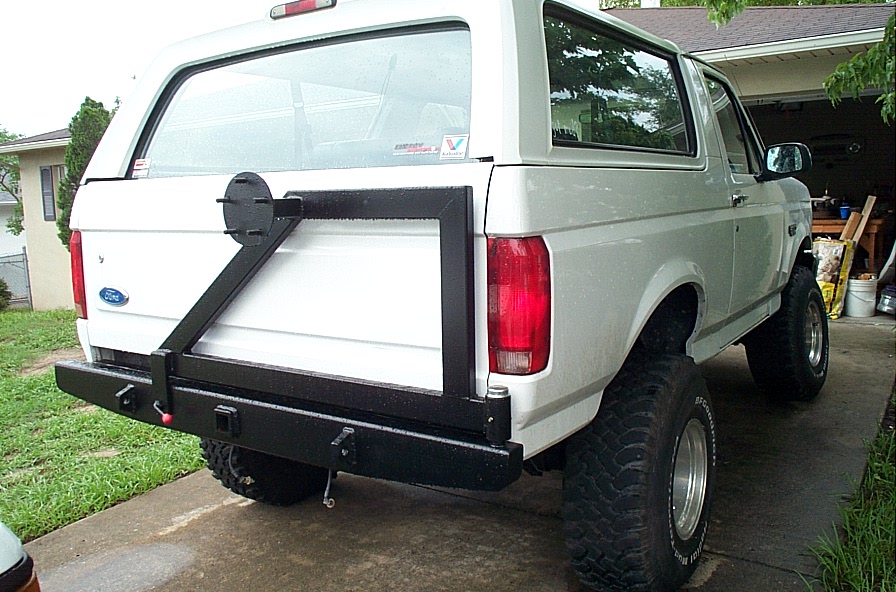 White lifted Ford Bronco rear view with black steel bumper and swing-out tire carrier