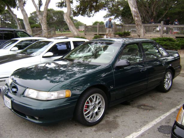 Dark green sedan with aftermarket wheels parked outdoors