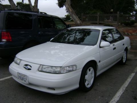 1991 Ford Taurus - White 1991 Ford Taurus sedan parked outdoors next to a dark SUV.