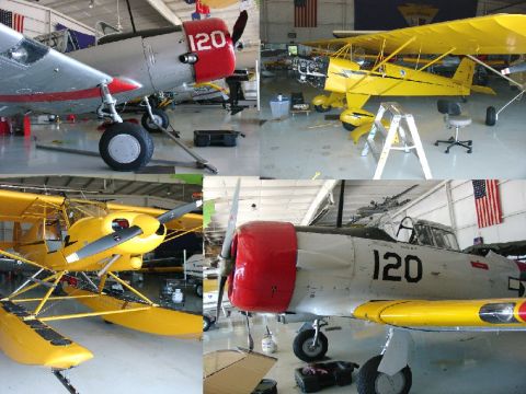 2003 Ford Crown Victoria - Multiple aircraft, including a yellow seaplane, are stored inside a hangar with American flags visible.