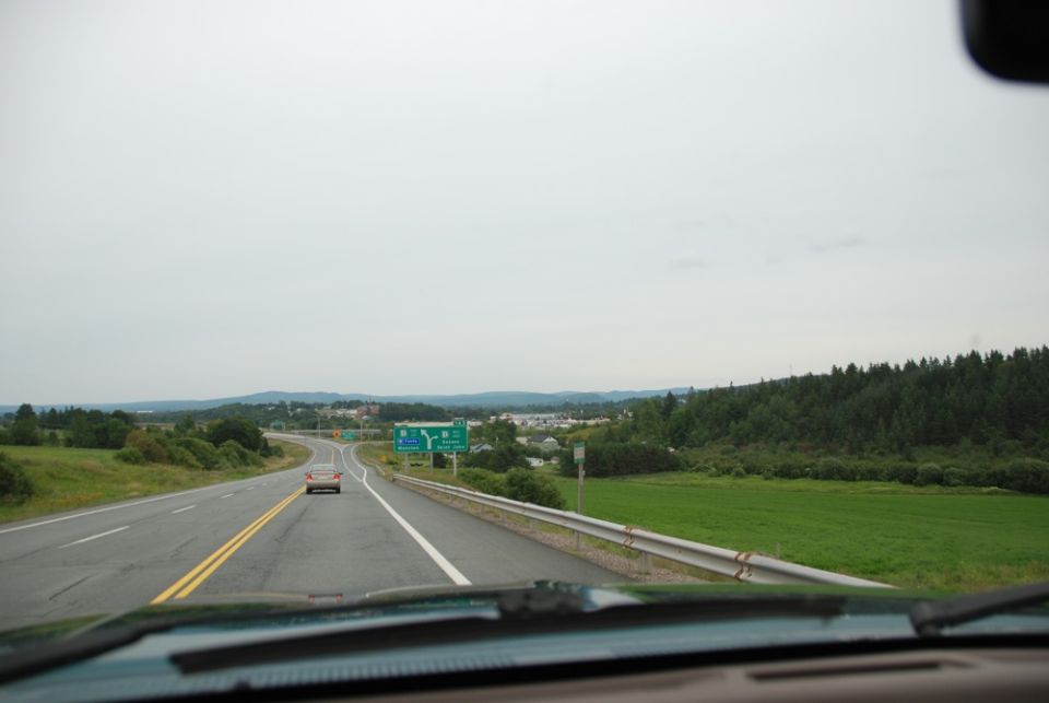 Highway scene with a red car and green exit signs