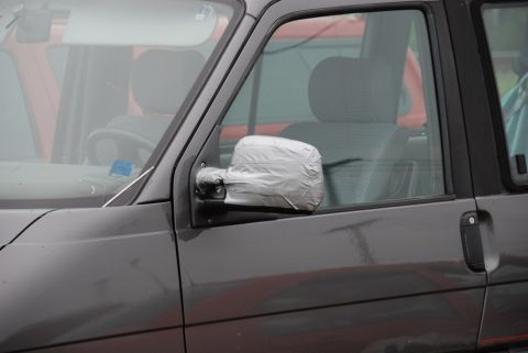 1996 Ford Bronco - A side mirror on a gray van has been temporarily repaired with duct tape.