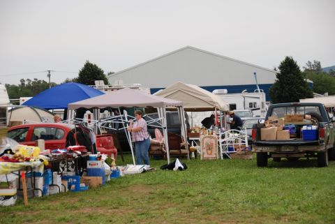1996 Ford Bronco - An outdoor market is set up with various tents and tables displaying goods, with several vehicles present.