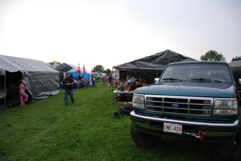 1996 Ford Bronco - A teal Ford F-series truck is parked on grass near tents and people at an outdoor gathering.