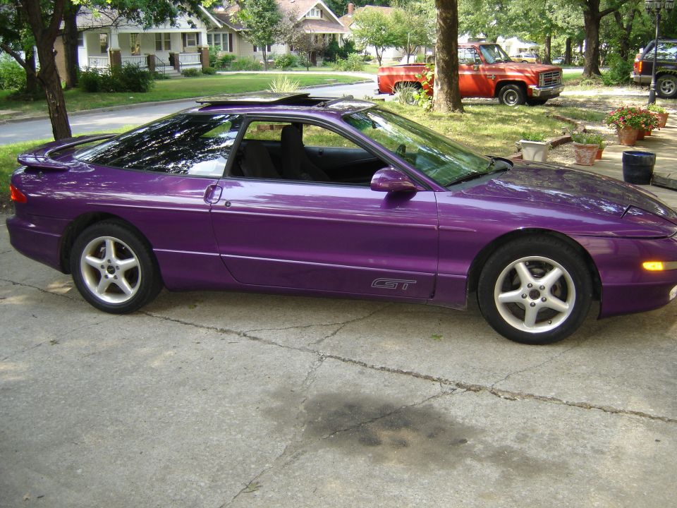 Purple 1994 Ford Probe GT parked on driveway, red pickup truck in background