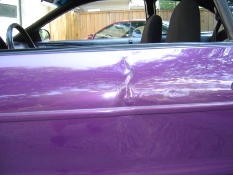 1994 Ford Probe - Close-up of a damaged purple car door, with another vehicle in the background.