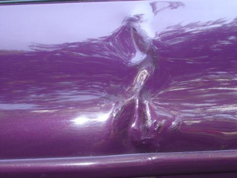 1994 Ford Probe - This photo shows significant damage to the side panel of a purple vehicle.