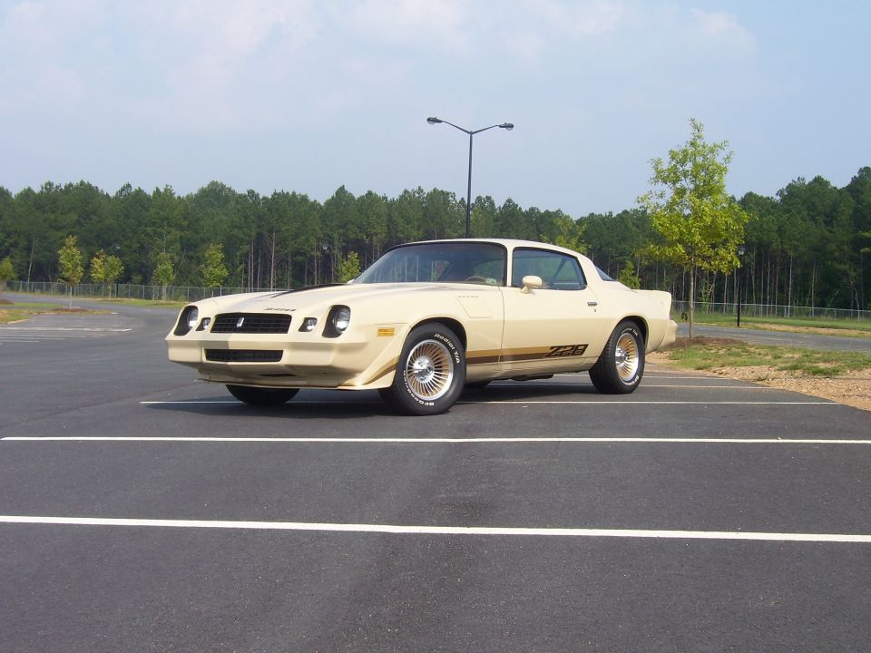 1979 Chevrolet Camaro Z28 parked in a lot, front 3/4 view. Beige paint with gold Z28 stripe
