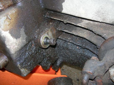 1984 Ford Bronco - Close-up of a greasy mechanical component with a visible bolt and bearing, resting on an orange jack.