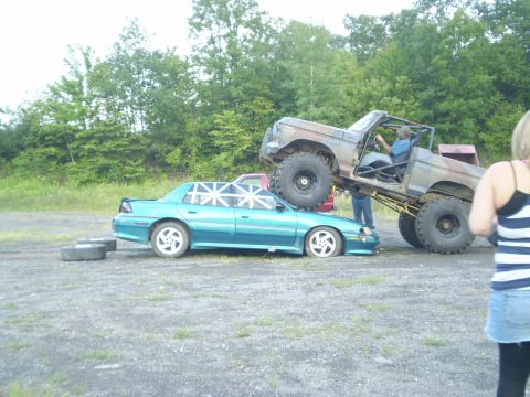 1979 Ford Bronco - A heavily modified truck is shown on top of a sedan, with a person inside the truck.