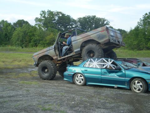 1979 Ford Bronco - A lifted, camouflaged 1979 Ford Bronco is shown crushing a teal sedan in a car crush event.