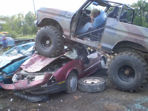 1979 Ford Bronco - A 1979 Ford Bronco is shown crushing several cars, with a person inside the Bronco.