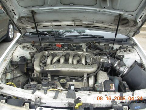 1995 Ford Taurus - The engine bay of a 1995 Ford Taurus is shown with the hood open.