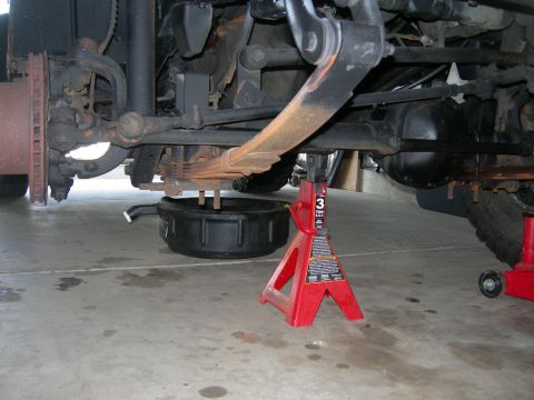 1991 Jeep Wrangler - The underside of a vehicle is shown, with leaf springs, a differential, and an oil drain pan visible.