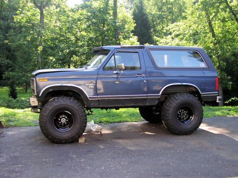 1986 Ford Bronco - Blue 1986 Ford Bronco lifted with oversized tires parked on a driveway.