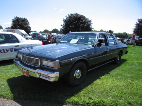 1991 Ford LTD Crown Victoria - dark blue boxy 1980s Chevrolet Caprice sedan displayed on grass with a Canadian flag front license plate.