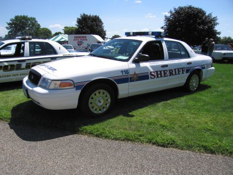 1991 Ford LTD Crown Victoria - white Ford Crown Victoria sheriff cruiser numbered 116 with a front push bar and roof lightbar parked on grass.