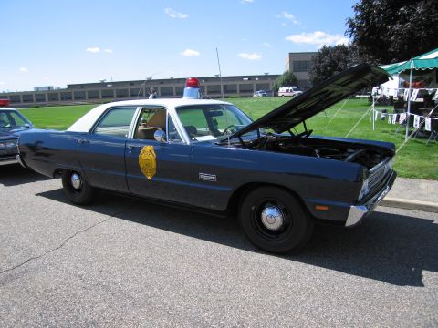 1991 Ford LTD Crown Victoria - blue and white late-1960s Plymouth police sedan with hood open, roof beacon and a gold star badge on the door.