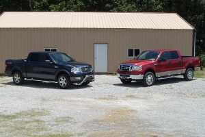 2008 Ford F-150 - Two pickup trucks are parked outside a tan building on a gravel lot.