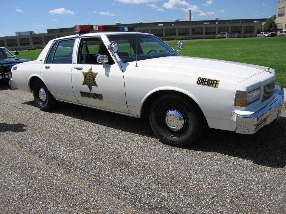 White Chevrolet Caprice SHERIFF cruiser with gold star and roof beacons