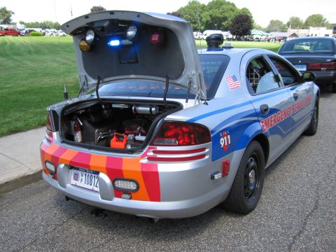 1991 Ford LTD Crown Victoria - Rear of a silver Emergency Service sedan with its trunk open displaying lights and rescue gear at an outdoor show.