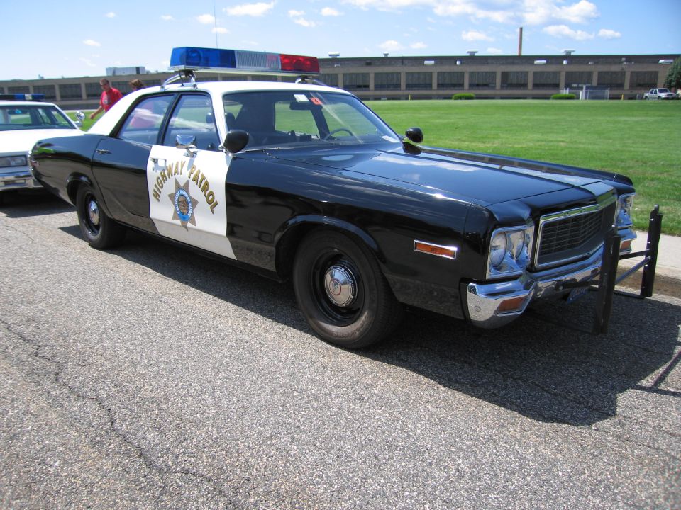 Black-and-white Highway Patrol sedan with chrome grille and roof light bar
