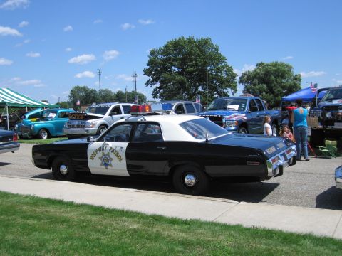 1991 Ford LTD Crown Victoria - black-and-white Highway Patrol police sedan with a white roof and star shield, displayed on grass among other show cars.