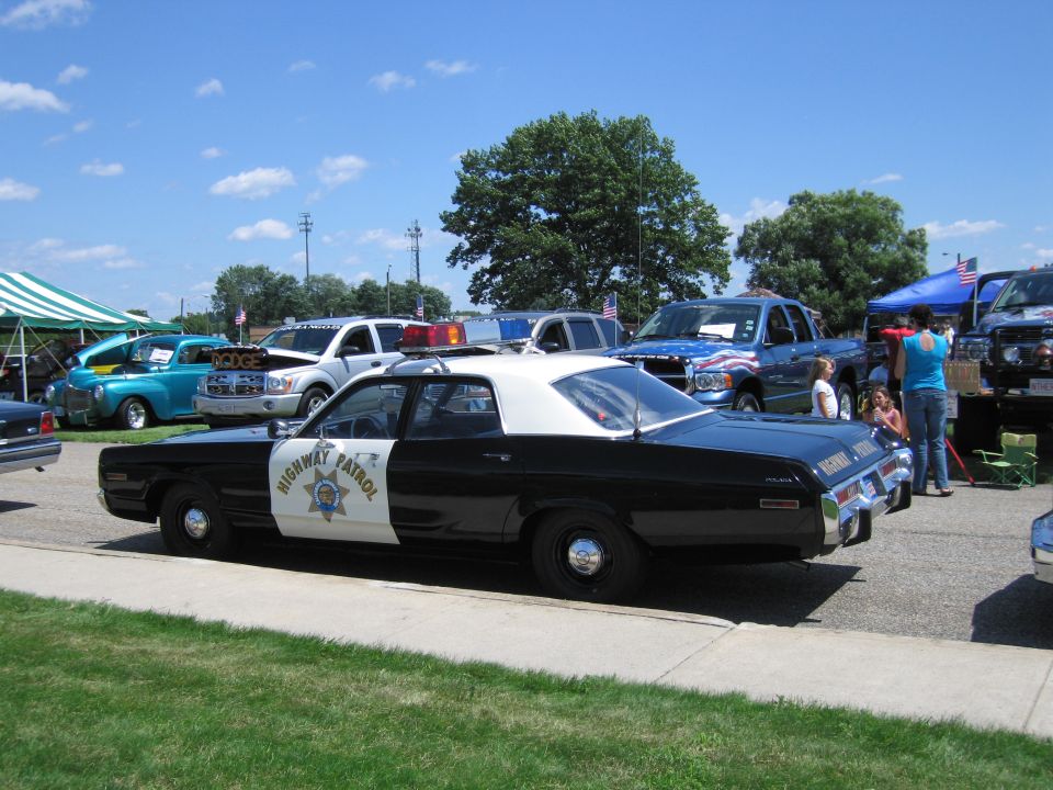Black and white Highway Patrol sedan with white roof at car show