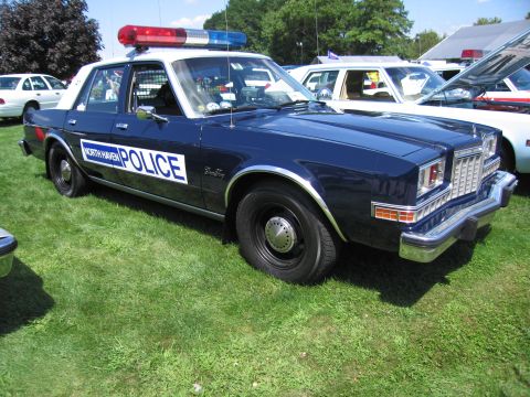 1991 Ford LTD Crown Victoria - dark-blue-and-white North Haven Police sedan with roof light bar and steel wheels parked on grass at a car show.