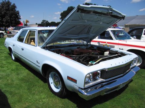 1991 Ford LTD Crown Victoria - light-blue Plymouth full-size sedan with its hood raised to reveal the engine, displayed on grass at a car show.