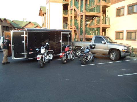 1995 Mercury Grand Marquis - A silver pickup truck is parked beside a black trailer, with three motorcycles lined up in front of the trailer.