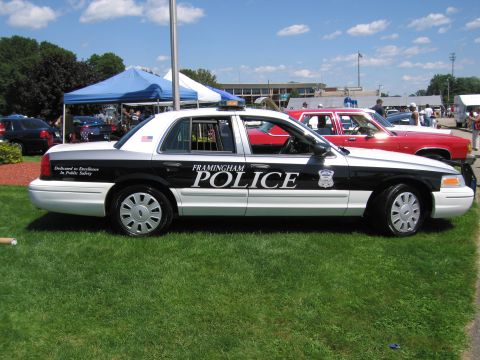1991 Ford LTD Crown Victoria - black-and-white Framingham Police Ford Crown Victoria sedan parked on grass at a show with a tent and cars behind it.