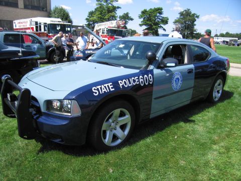 1991 Ford LTD Crown Victoria - blue-and-light-blue Massachusetts State Police Dodge Charger, unit 609, parked on grass with fire apparatus behind.