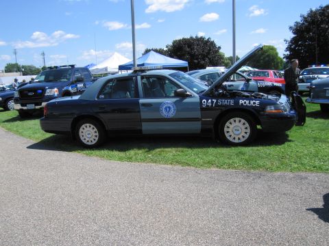 1991 Ford LTD Crown Victoria - Massachusetts State Police Ford Crown Victoria, unit 947, sits with its hood open on grass among other display cars.