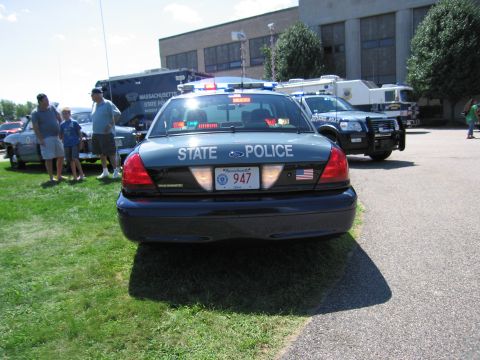 1991 Ford LTD Crown Victoria - Rear view of a Massachusetts State Police Ford Crown Victoria, unit 947, on grass with spectators and other vehicles behind.